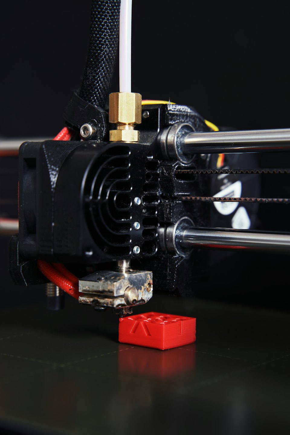 3D-Drucker extrudiert rotes Filament auf das Druckbett.